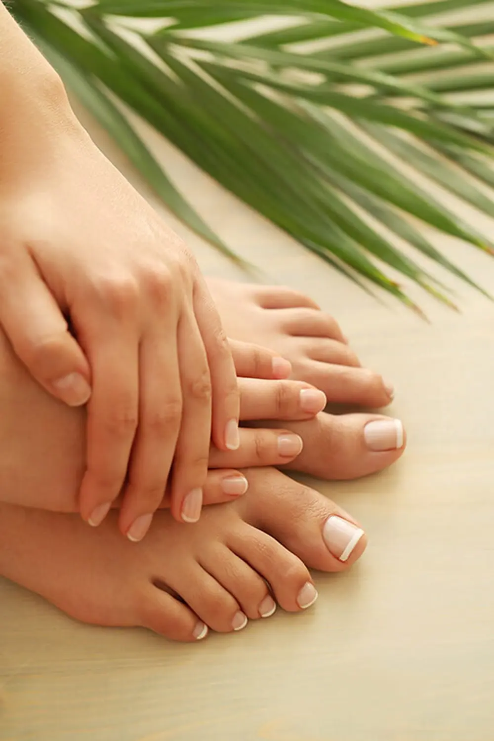 Close-up of bare feet and hands, resting on a light wooden surface